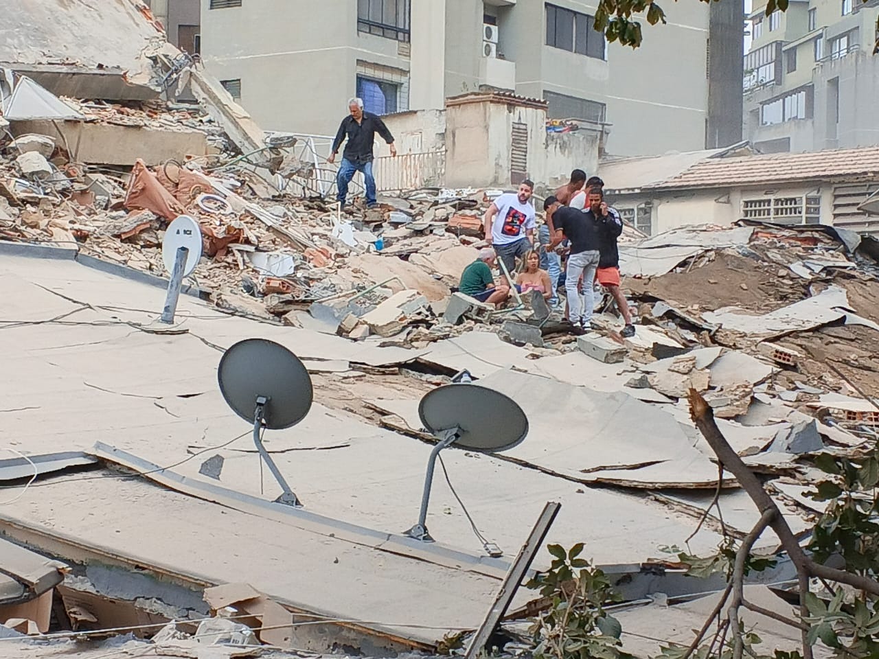 Pessoas sobre escombros de um edifício após o terremoto
